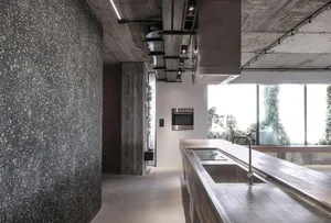 Modern kitchen with minimalist design, featuring a concrete countertop and a steel sink.