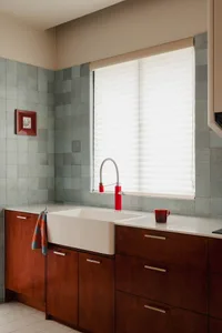 Modern kitchen featuring tile backsplash, concrete countertops, and wooden cabinets in front of a large window.