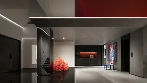 A modern lobby featuring exposed concrete walls, a red accent wall, and minimalist design elements.
