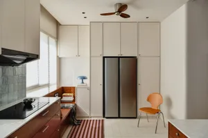 A modern residential kitchen featuring stainless steel appliances, white cabinetry, and a striped rug.