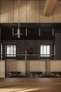 Industrial restaurant kitchen with metallic counter and stools.