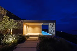 A modern, minimalist residential exterior with a concrete facade at night time.