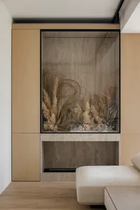 Modern minimalist living room featuring a fireplace with a slide design, wooden cabinetry, and shelves.