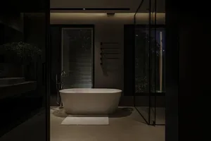 A modern bathroom with a freestanding bathtub, concrete floor, and large windows overlooking the outdoors.