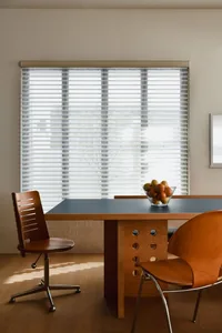 A modern dining room featuring minimalist design with wood furniture and blinds