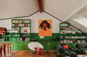 A modern living room with green shelves, a white papasan chair, and a green sofa under a sloped white ceiling.