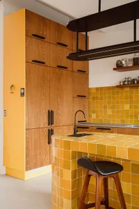 A modern kitchen featuring bright yellow square tiles on the walls and countertops.