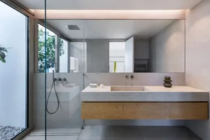 Modern minimalist bathroom with concrete sink and walls, glass shower enclosure, and large mirror.