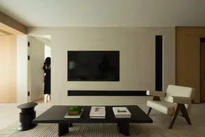 Modern minimalist living room featuring a wooden table and a wall-mounted television.