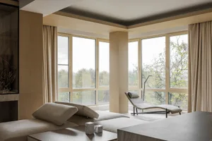 Modem living room with neutral-toned decor and large windows overlooking trees.