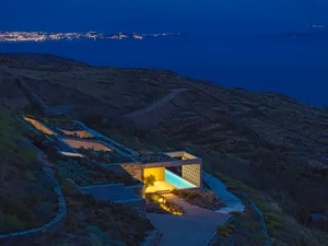 Modern residential architecture featuring concrete structures on a hilly landscape at night.