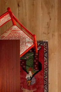 A red-framed chair with a white cushion on a wooden floor.