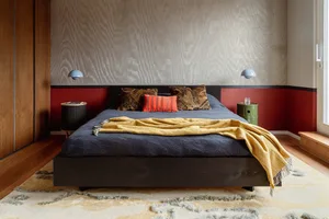 A modern bedroom featuring a dark wooden bed and a geometric patterned rug.