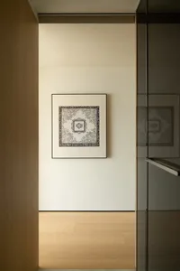 A decorative paper art framed in a minimalist frame hanging on a beige wall.
