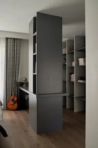 A neatly organized home office space featuring grey shelves and wooden floors.