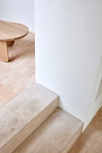 A minimalist concrete staircase with a smooth, textured surface, placed against a white wall in a contemporary interior desig