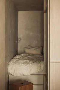 A minimalist bedroom with concrete walls and a bed.