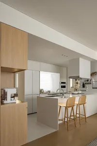 Open-plan residential kitchen featuring minimalist design with white cabinets and no visible clutter.