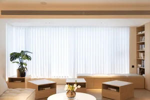 A modern minimalist living room with white curtains, wooden furniture, and a potted plant.