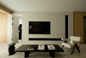 A modern living room with a black and white color scheme, featuring a flat-screen TV mounted on a wall, a black coffee table,