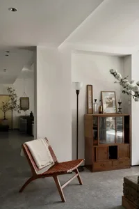 A modern living room featuring a wood armchair with a concrete floor, providing a comfortable and stylish lounge area.