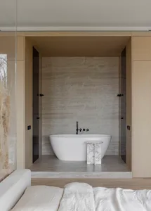 A modern minimalist bathroom with marble accents, featuring a freestanding bathtub and wooden cabinets.