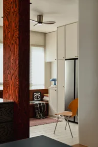 A modern minimalist living room with wood furniture, white cabinetry, and a striped rug.