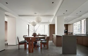 A modern residential kitchen with wood accents featuring a round dining table and chairs, a stone countertop, and a view of t
