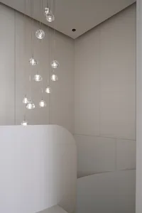 Minimalist bathroom with hanging glass light fixtures and curved white structure