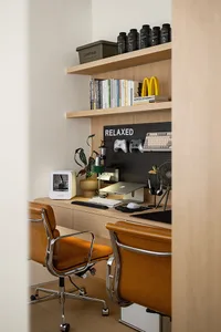 A minimalist home office with a wooden desk and orange leather chairs.