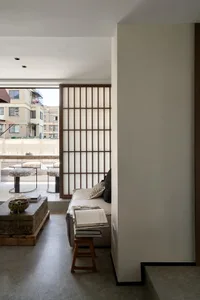 Modern and minimalist living room with a wooden sofa, stool, and decorative items.