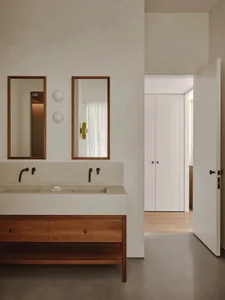 Minimalist modern bathroom featuring a concrete countertop with dual sinks and wooden cabinetry below.