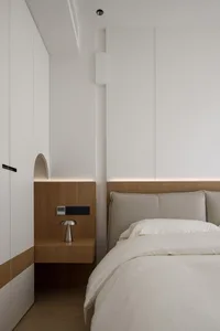 A modern bedroom with white paneling on the walls and a wooden headboard and nightstand.
