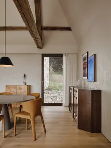 Modern dining room with a wooden table, glass chairs, and a glass wall