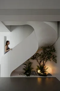 A modern interior featuring a white concrete staircase with a small garden at the bottom.