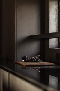 現代廚房檯面採用深色木質材質，黑色盤子上擺放葡萄，背景有小黑碗。