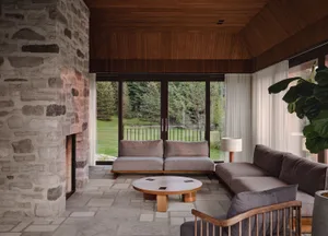 A cozy, modern living room with stone walls, a wooden ceiling, and comfortable furniture.