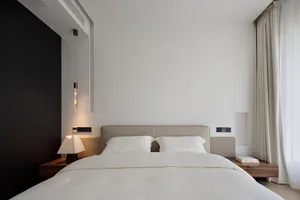 A minimalist bedroom with a bed adorned with white bedding and a hanging light fixture.