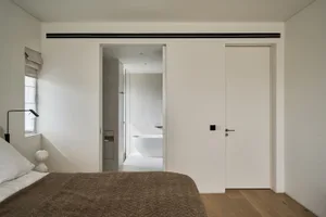 Minimalist bedroom with wooden flooring and a large bed.