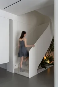 A woman wearing a dress walks up a modern minimalist staircase made of marble.