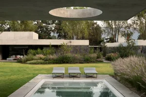 A modern residential exterior featuring concrete and lush greenery.