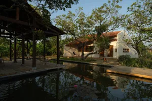 A waterfront home with a wooden walkway leading to a reflection in the water.