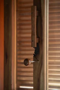 A close-up view of a wooden door handle and latch mechanism on a wooden door, highlighting the craftsmanship and texture of t