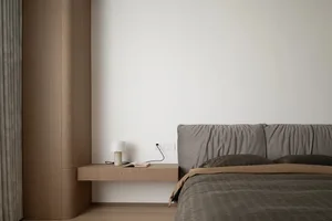 Minimalist bedroom with a floating nightstand, upholstered bed, and wood elements.