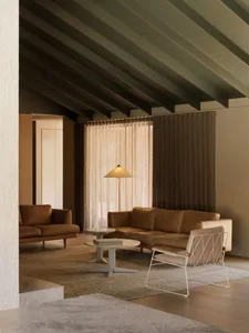 A minimalist living room featuring brown leather sofas under a ceiling with exposed wooden beams.