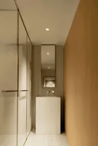 Modern bathroom with concrete walls and floor, featuring a simple pedestal sink and glass shower enclosure.