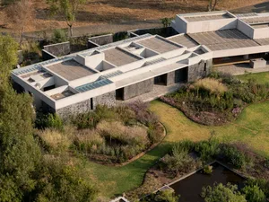 A modern concrete residential building with a green lawn and garden.