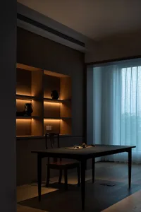 A modern dining room featuring wooden shelves and a dark wood table with a tea set.