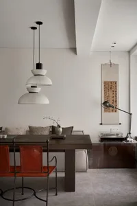 A modern interior design featuring a wooden dining table, leather chairs, and minimalist decor elements.