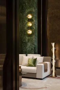 A modern living room featuring a white sofa with green and brown accents, illuminated by a unique light fixture, set against 